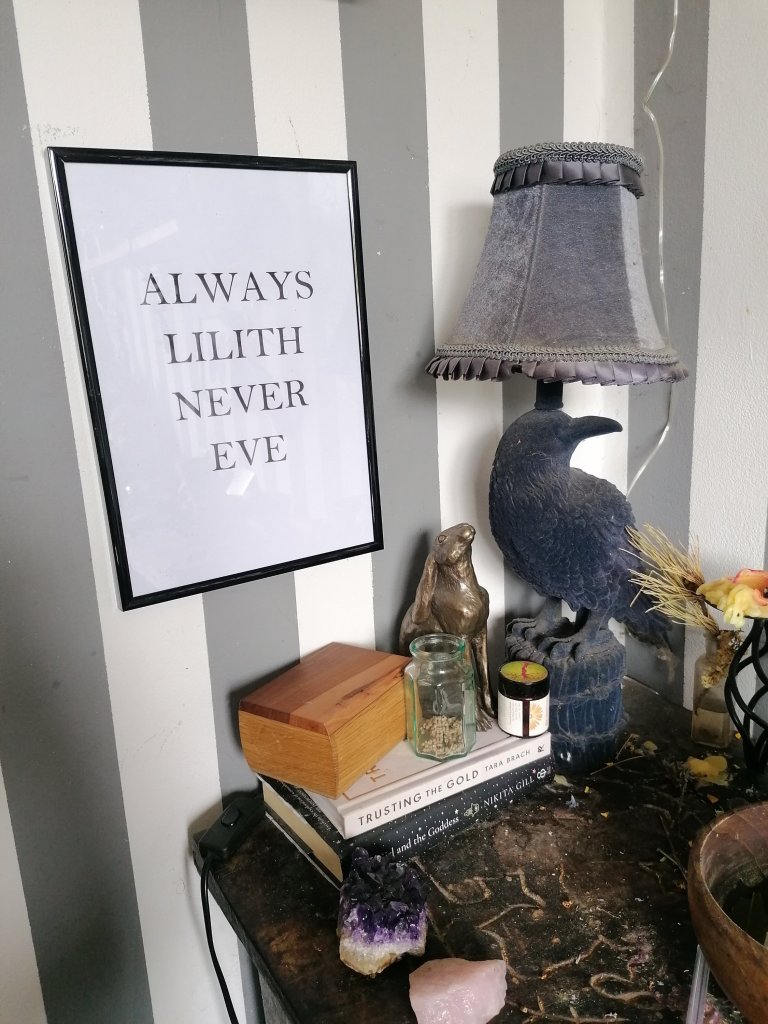 Phot of a dressing table with crystals, and a crow lamp and a hare statue. A poster on the wall reads "always Lilith never eve"